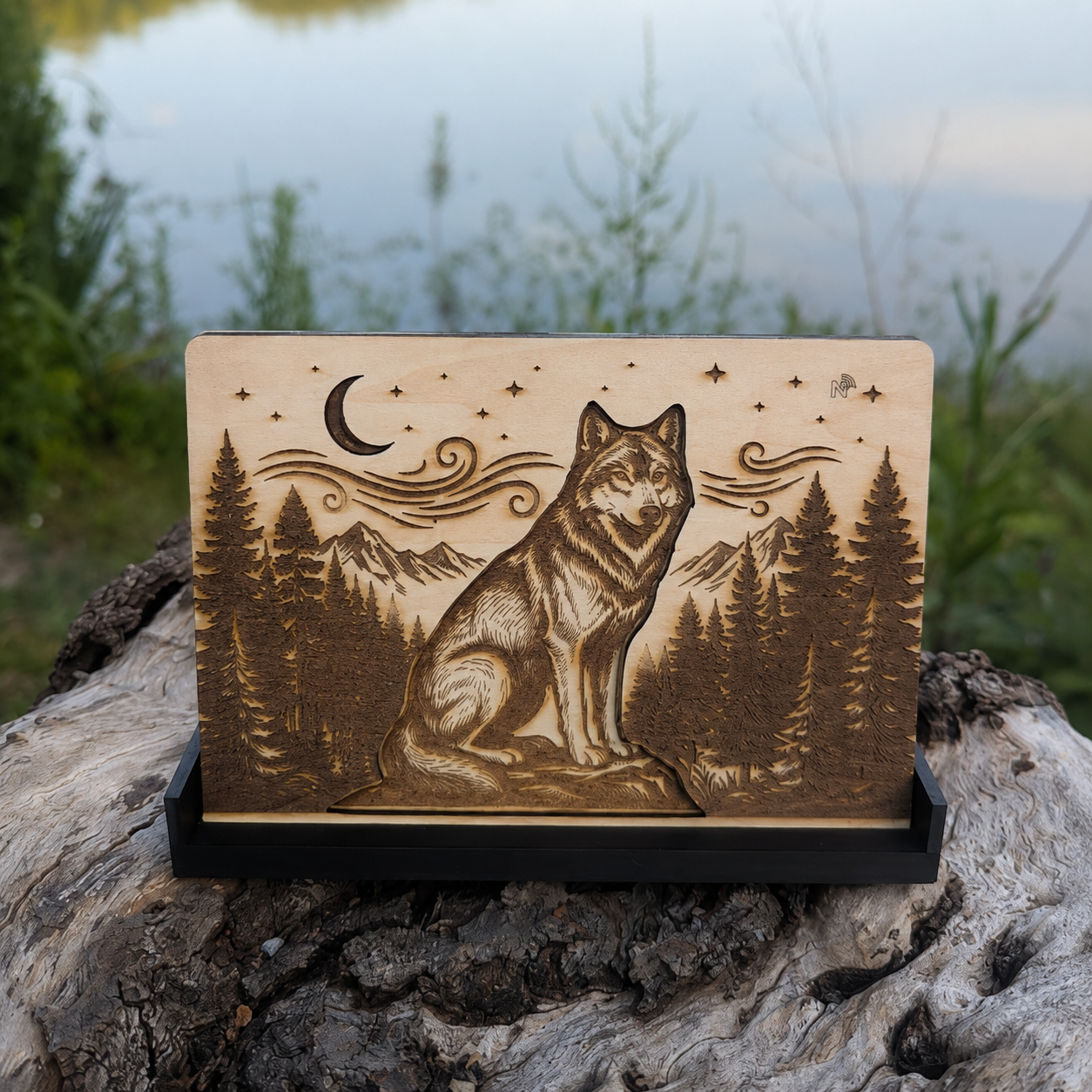 Totem NFC loup gravé sur bois de tilleul avec effet de profondeur visible au centre et paysage nature en arrière-plan au bord d’un lac.